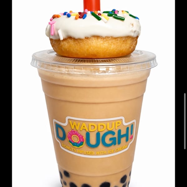 Waddup Dough! Black Milk Tea Boba Shake with a white-frosted, sprinkle-covered donut on top.